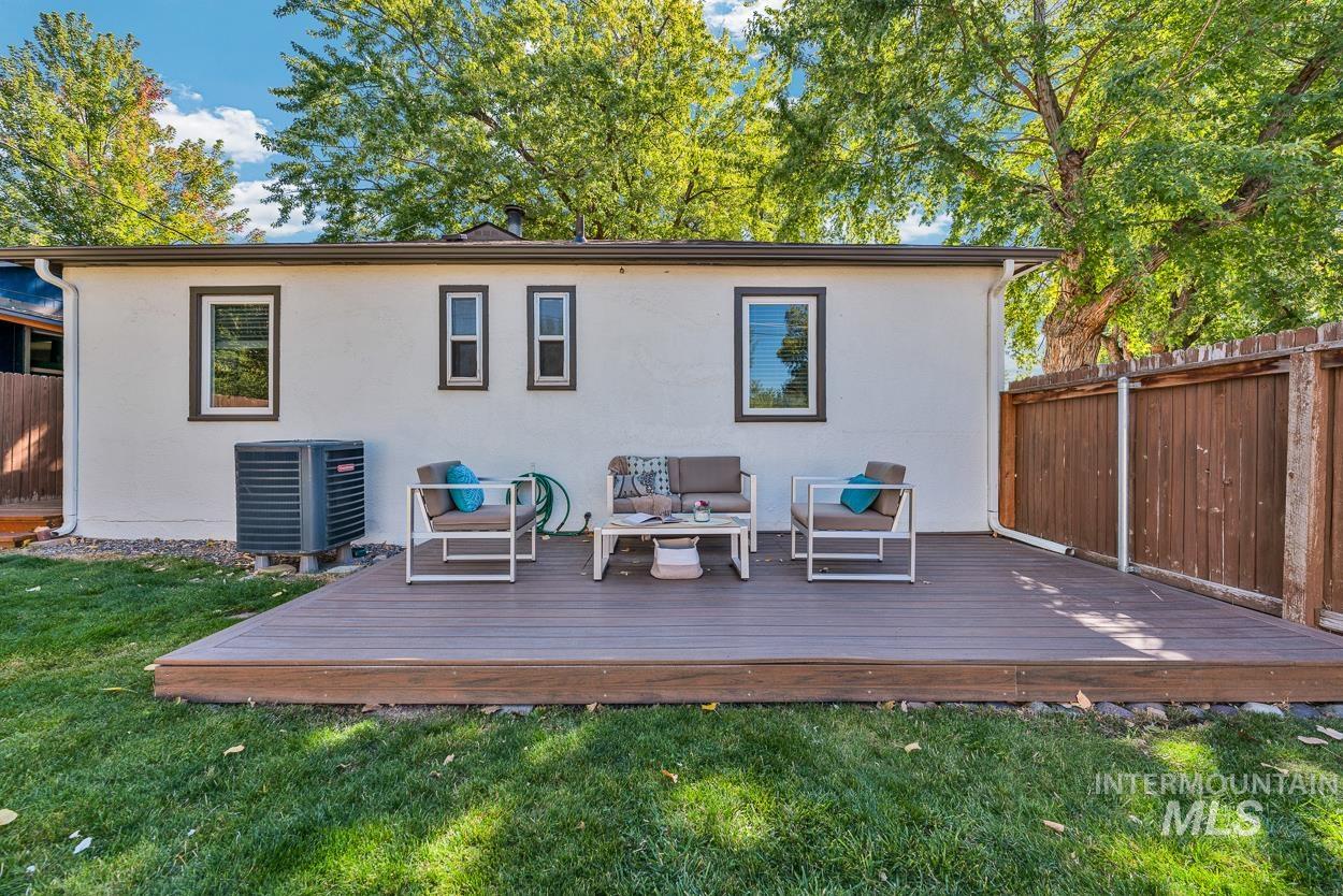 Back of property featuring a wooden deck, stucco siding, and an outdoor hangout area
