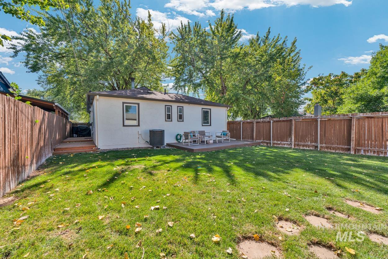 Rear view of house featuring a wooden deck, stucco siding, and a fenced backyard
