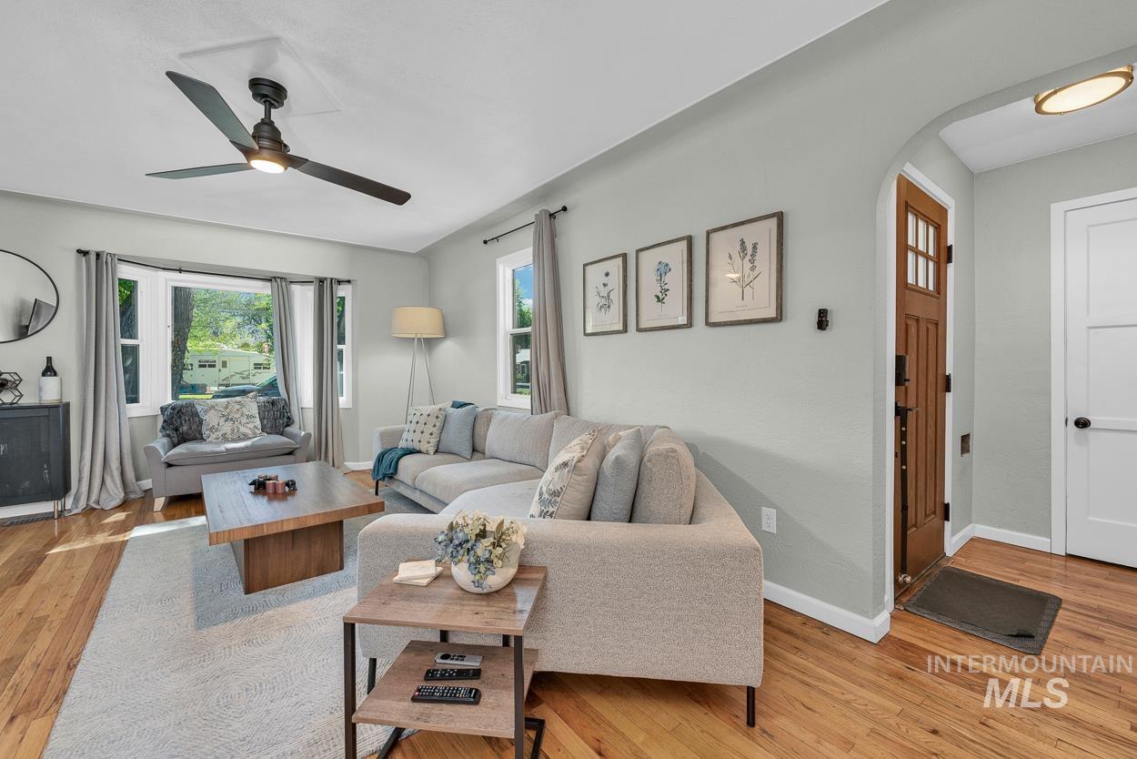 Living area featuring light wood-type flooring, arched walkways, and ceiling fan
