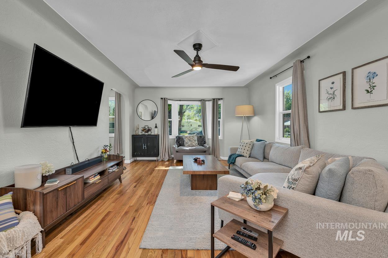 Living room featuring light wood-style floors, a ceiling fan, and a textured wall