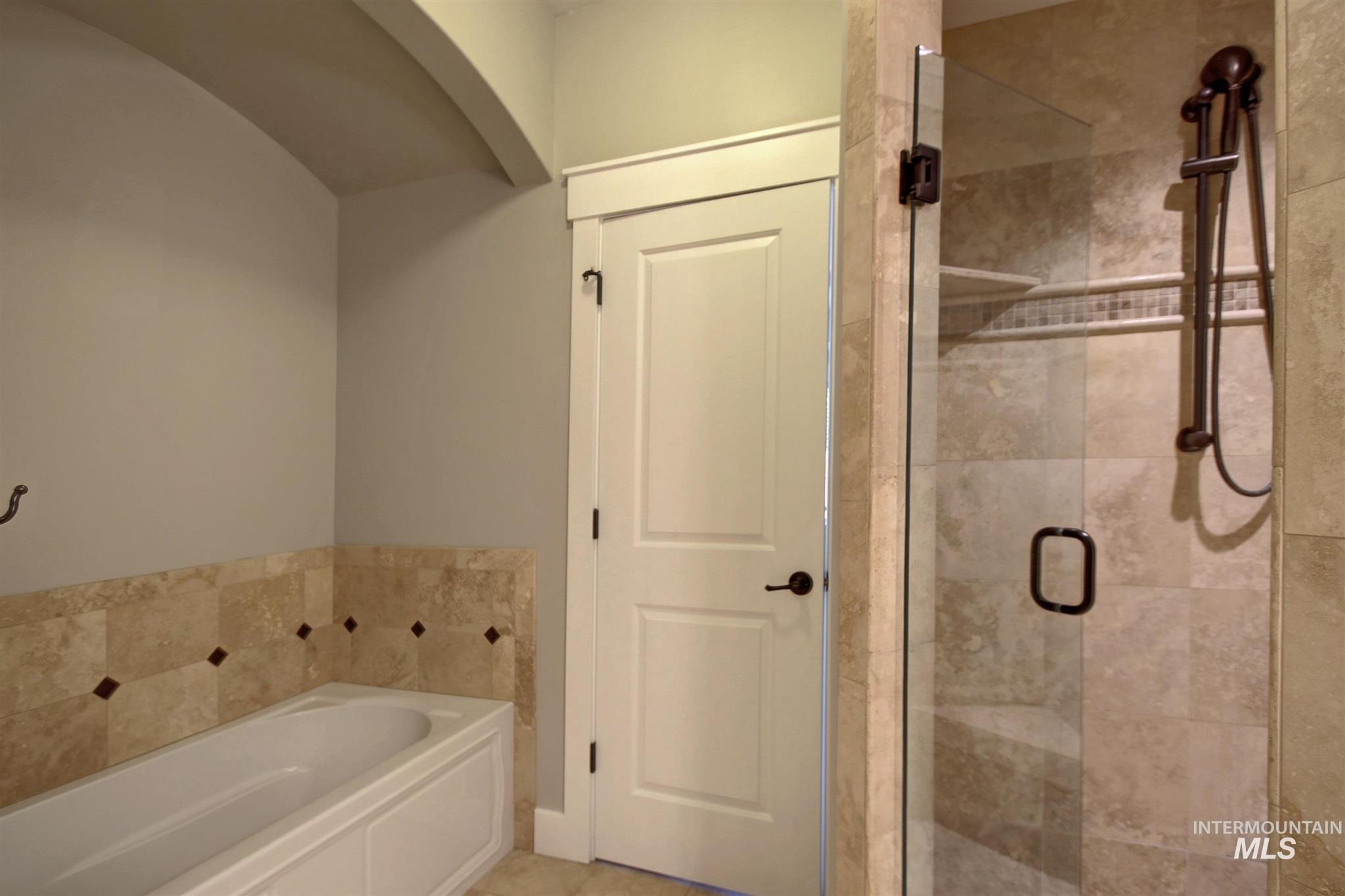 Bathroom featuring a garden tub, a shower stall, and tile patterned flooring