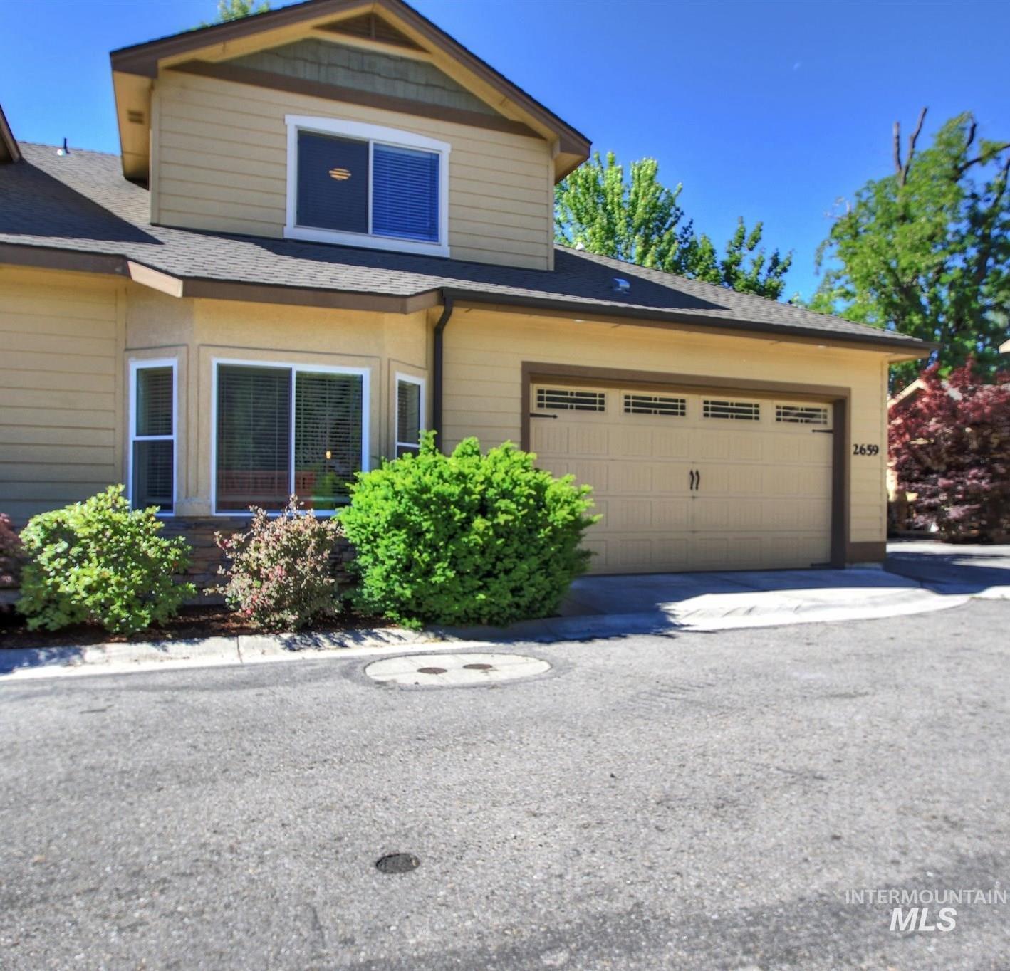View of front of home featuring roof with shingles, driveway, and a garage