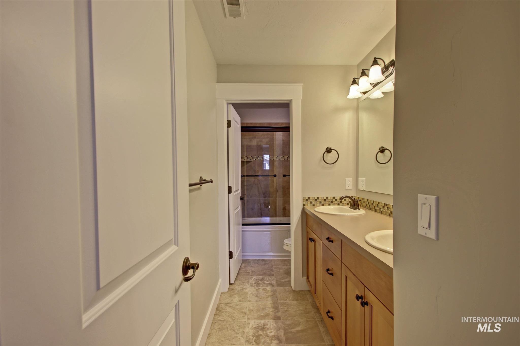 Bathroom featuring double vanity and shower / washtub combination