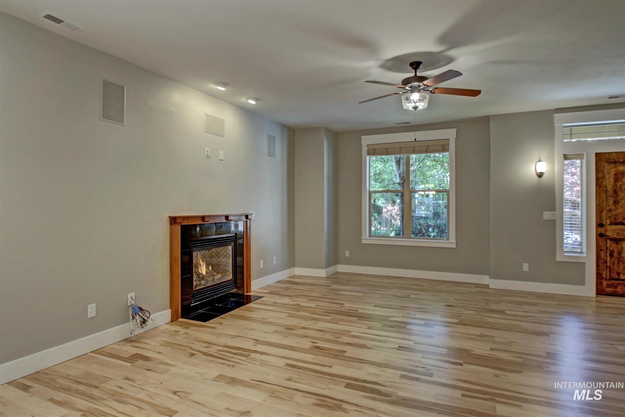 Unfurnished living room with a fireplace with flush hearth, light wood-style floors, and ceiling fan