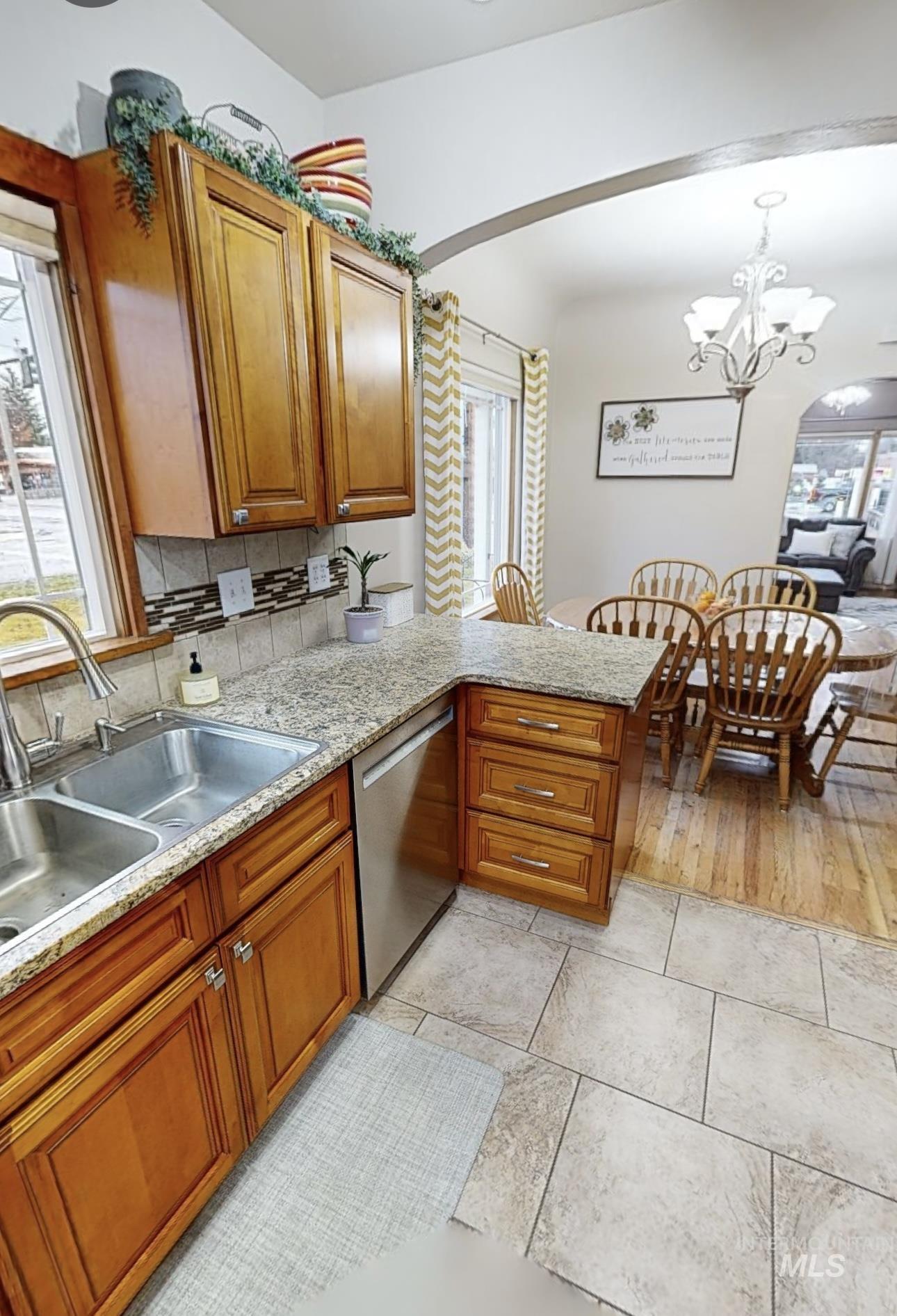 Kitchen featuring wood finish cabinetry, light stone counters, and arched walkways