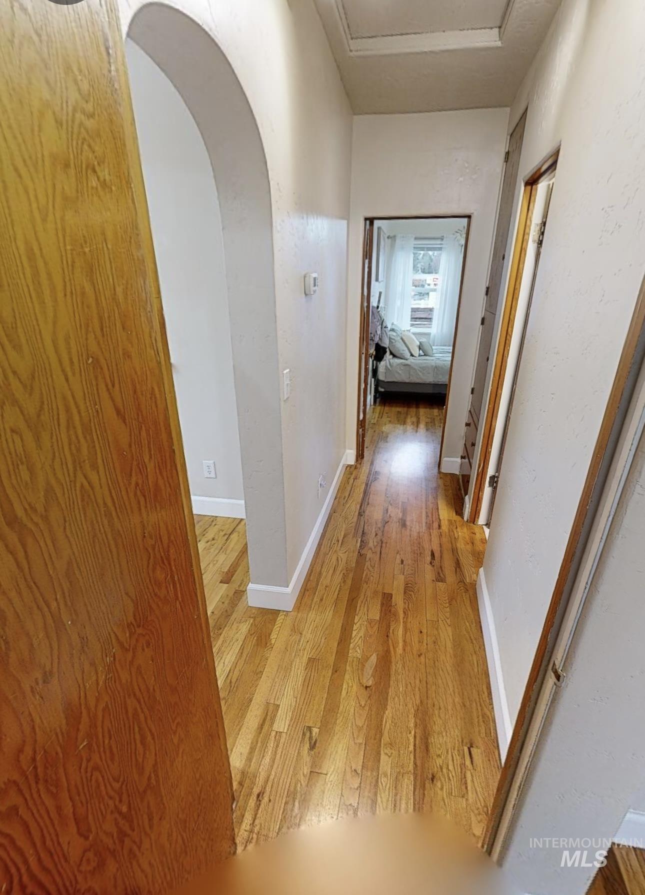 Hallway featuring light wood-style floors and arched walkways