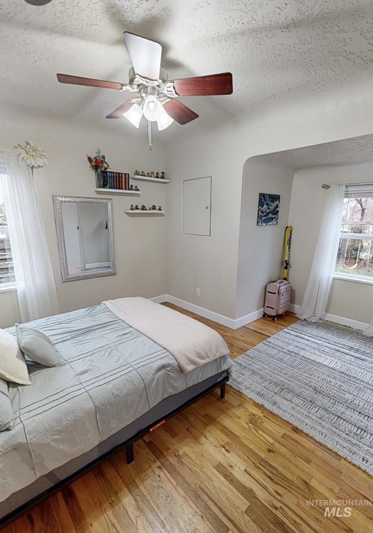 Bedroom featuring light wood-style flooring, a textured ceiling, and ceiling fan