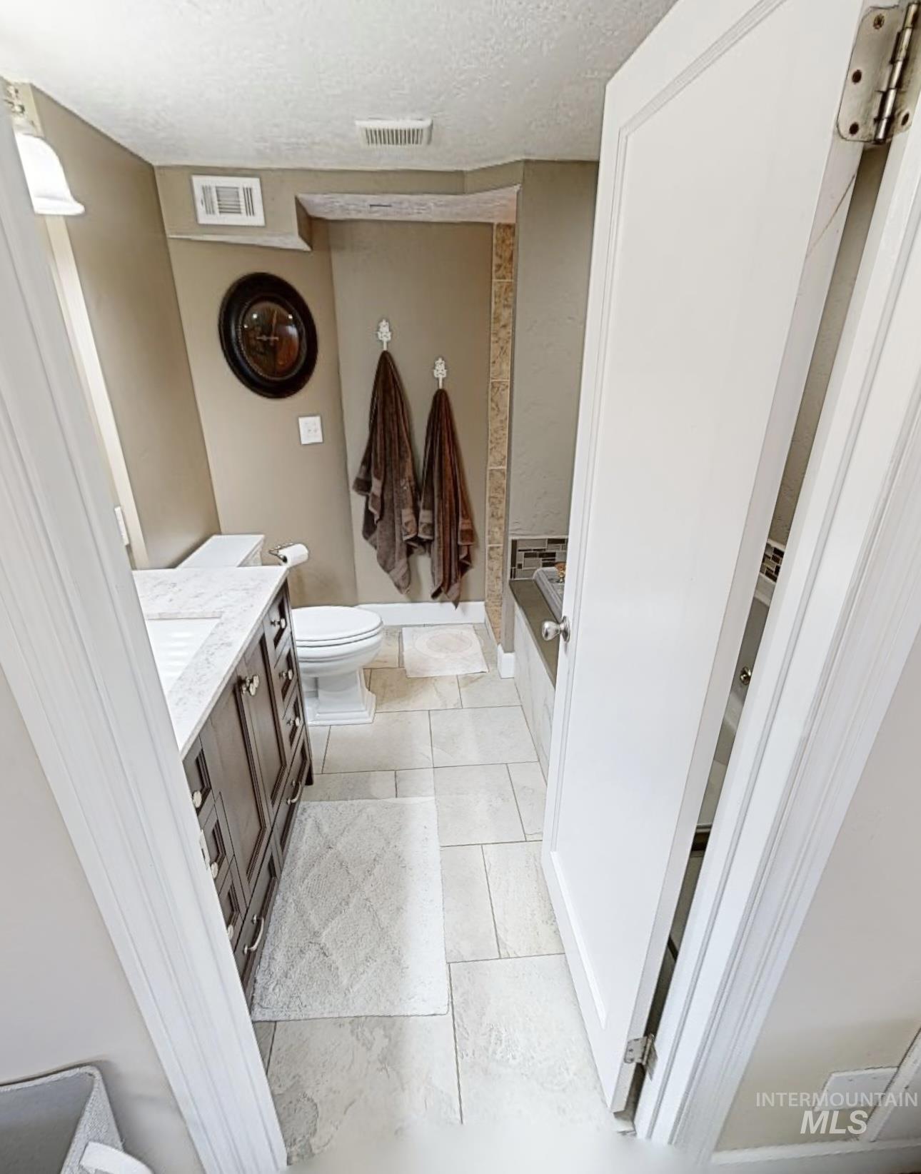 Bathroom with vanity, a textured ceiling, and a bath
