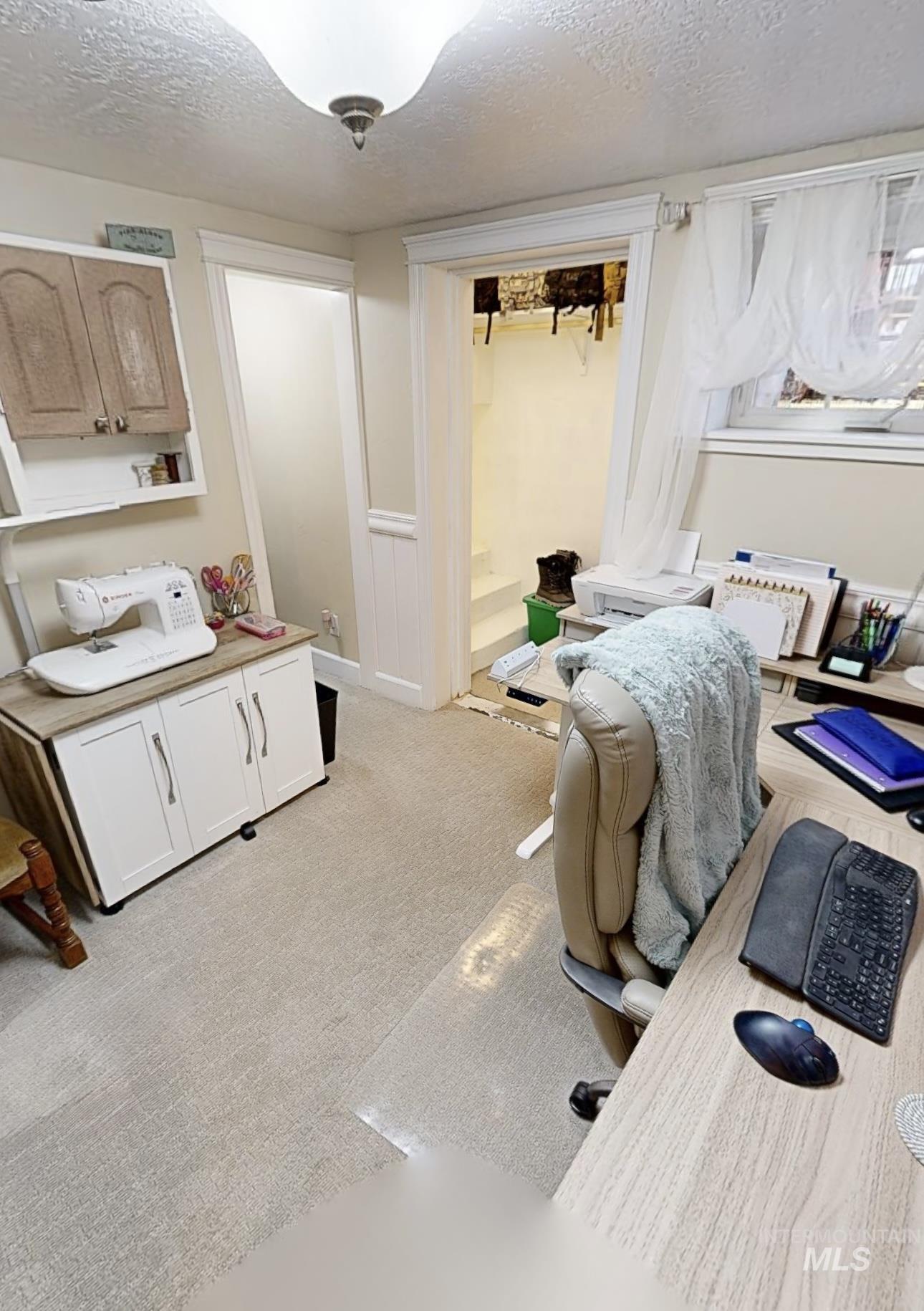 Home office featuring a textured ceiling and light colored carpet