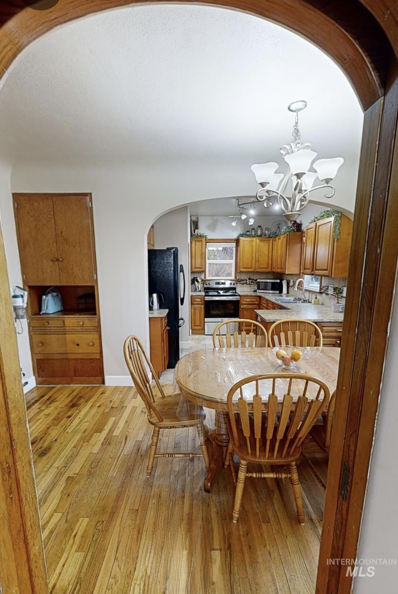 Dining room featuring arched walkways, a chandelier, and light wood finished floors