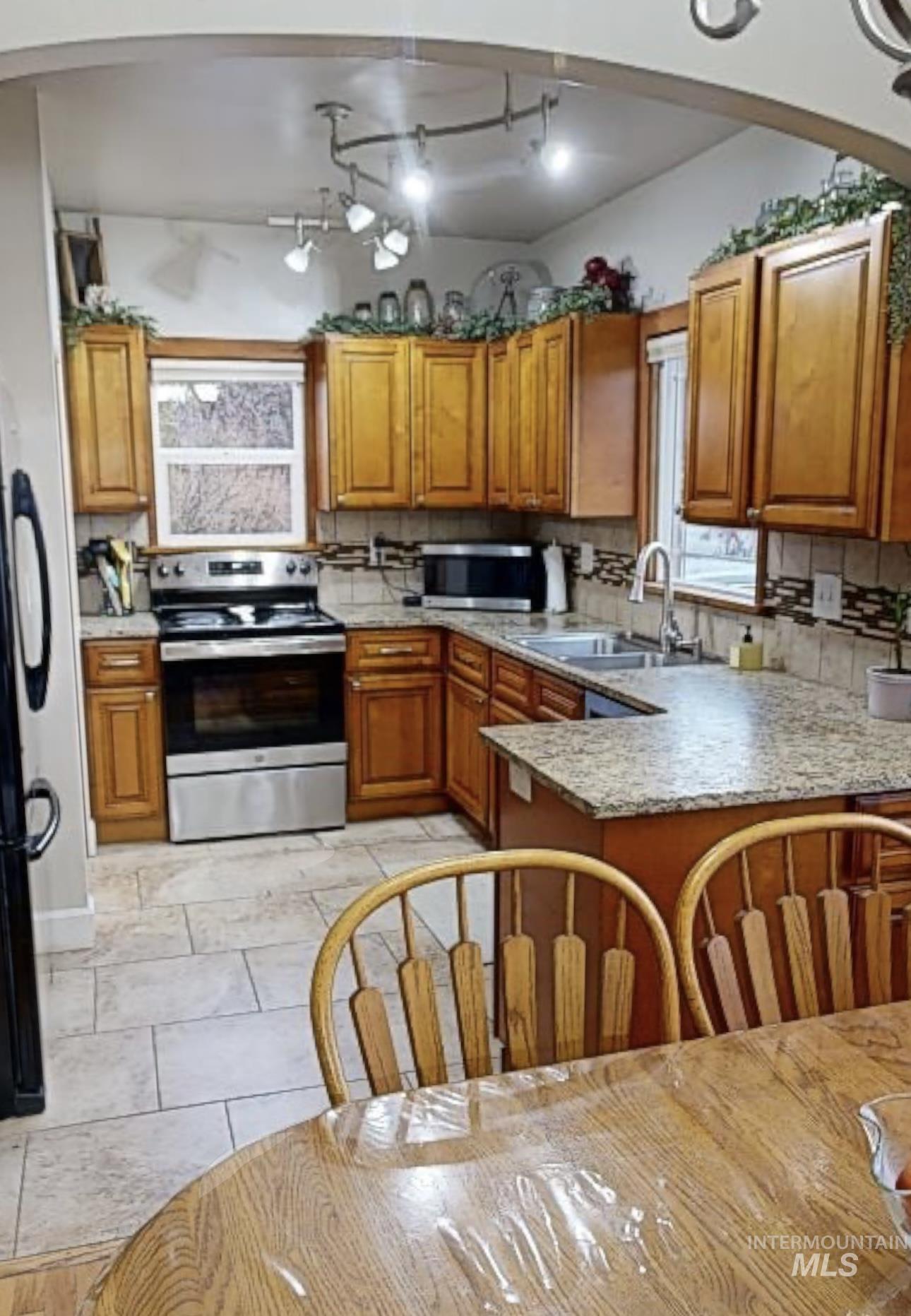 Kitchen with stainless steel appliances, wood finish cabinets, arched walkways, and tasteful backsplash