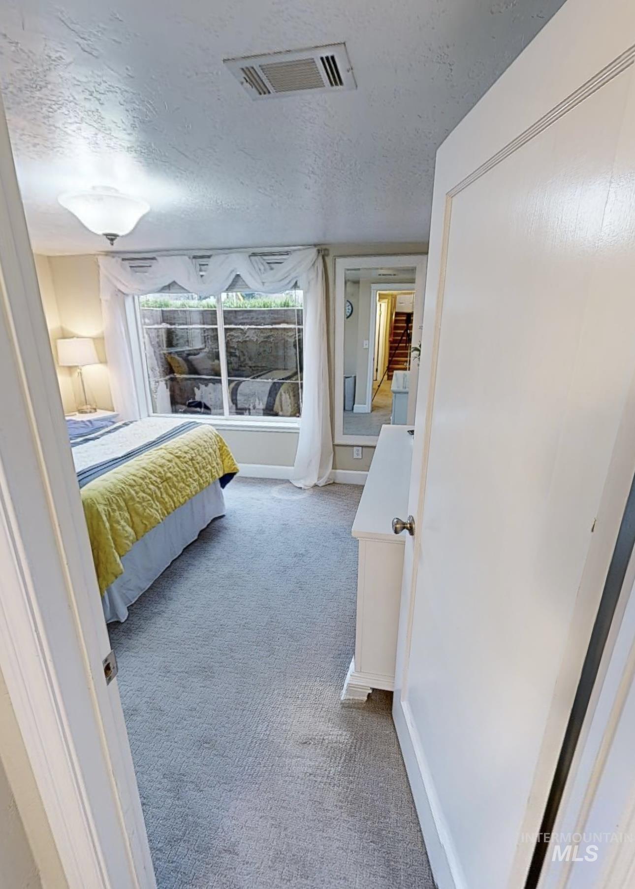 Bedroom featuring light carpet and a textured ceiling