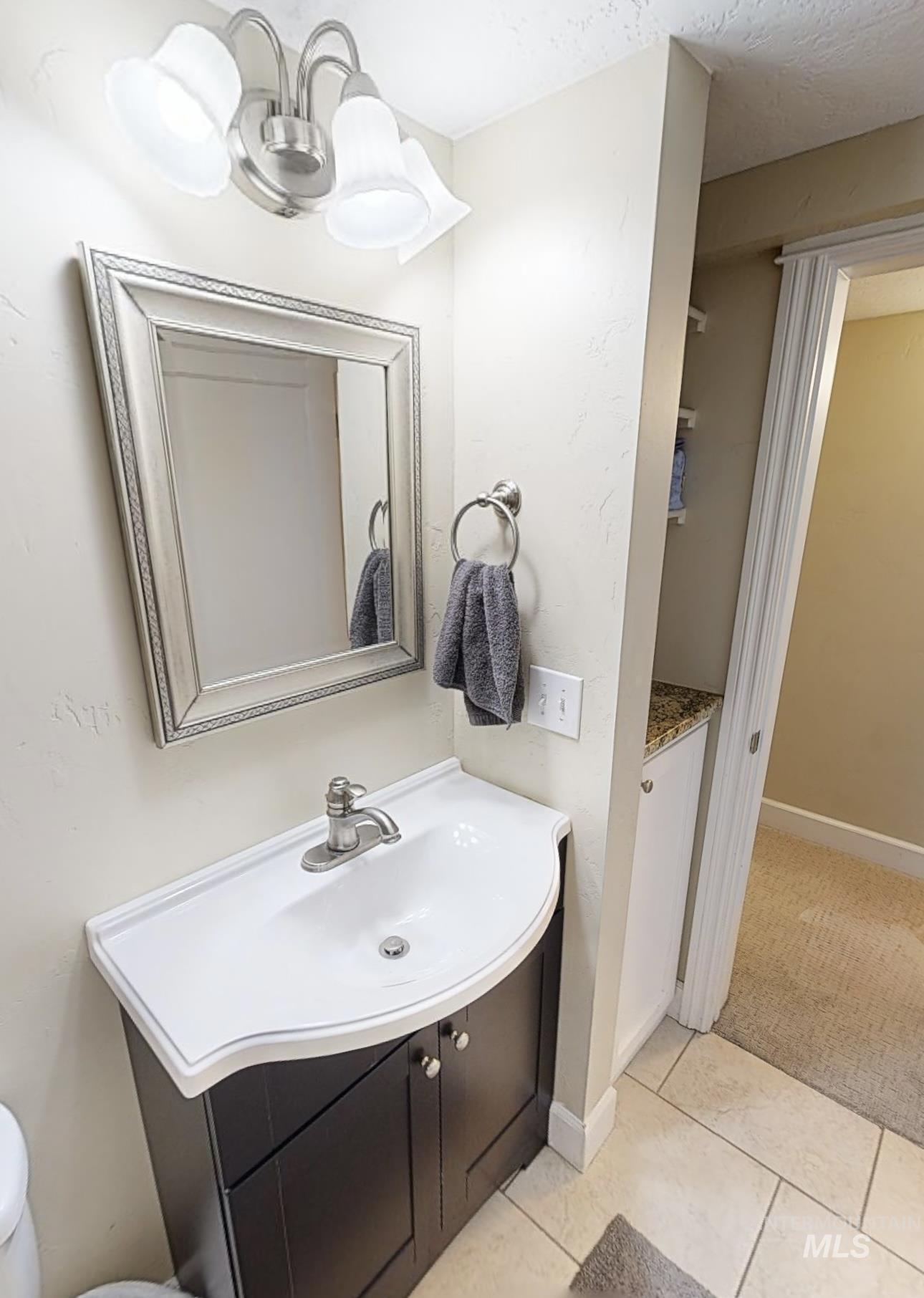 Bathroom featuring vanity, hanging lights, and light colored carpet