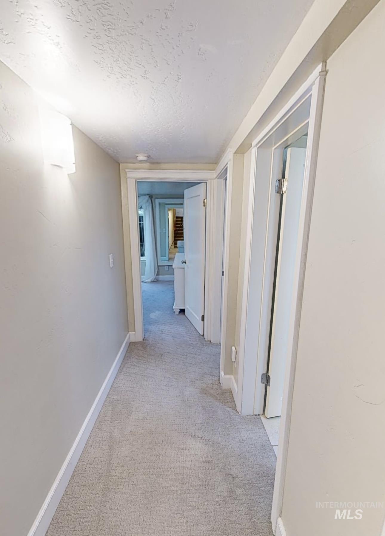 Hall with light carpet and a textured ceiling