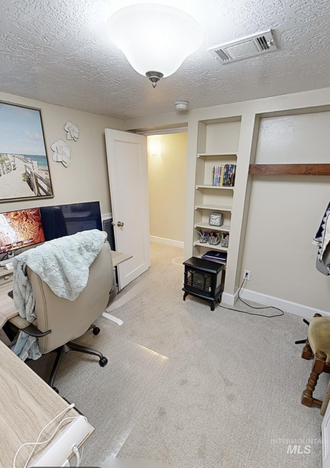 Carpeted office space featuring a textured ceiling and built in features