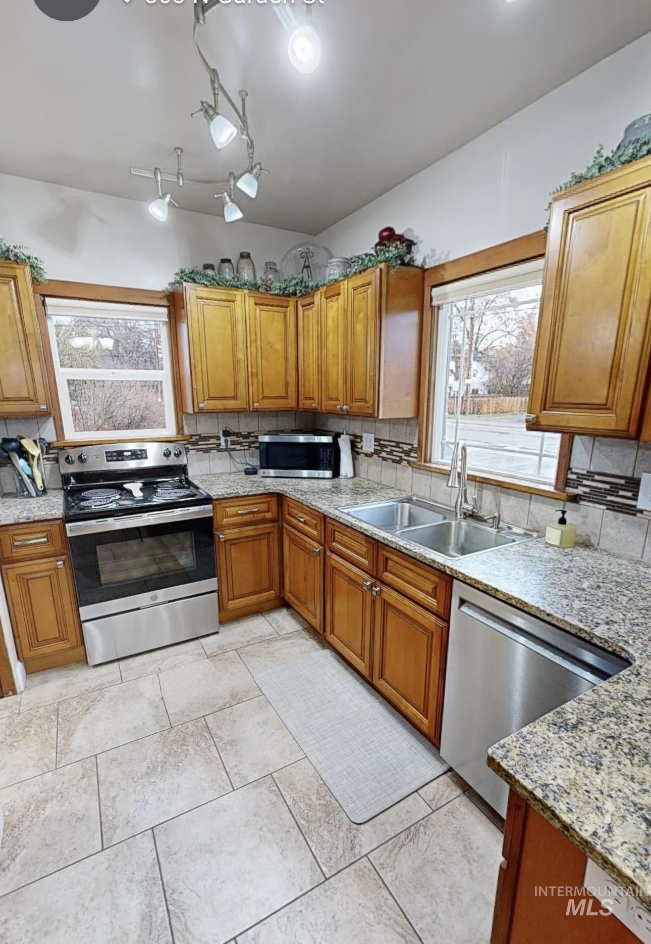 Kitchen featuring wood finish cabinets, stainless steel appliances, and light stone counters