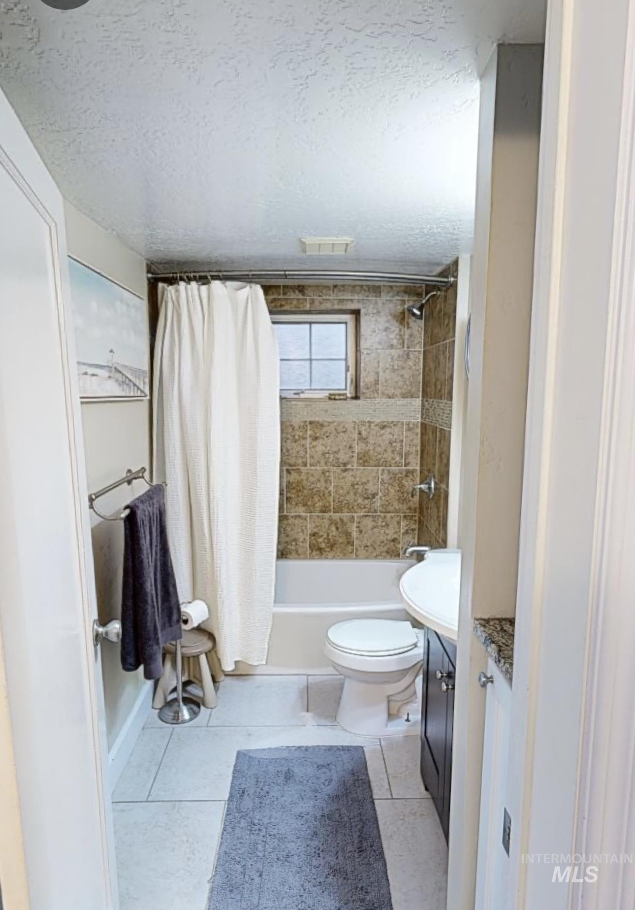 Bathroom featuring vanity, a textured ceiling, shower / tub combo with curtain, and light tile patterned floors