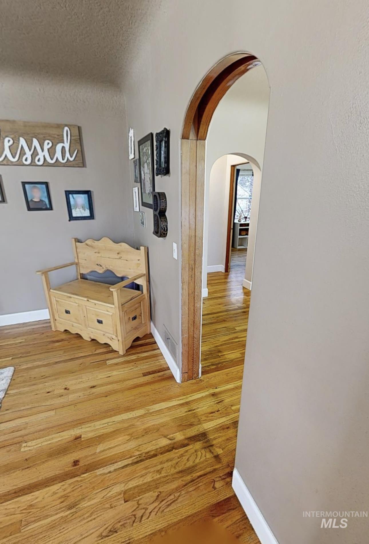 Hall featuring light wood finished floors and arched walkways