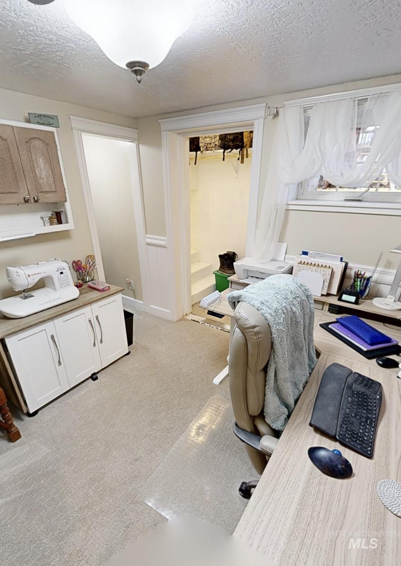 Office area featuring a textured ceiling and light colored carpet