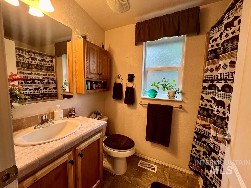 Full bath with a textured wall, vanity, and a shower with curtain