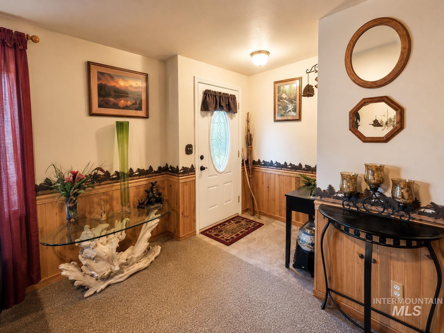 Entryway featuring wood paneling with decorative trim, neutral-toned walls, and a light-colored carpet