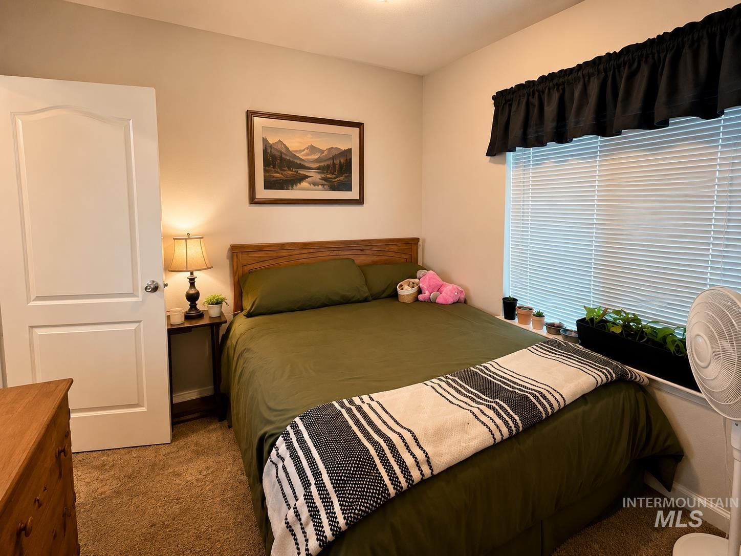 Carpeted room featuring a window with horizontal blinds and a dark valance
