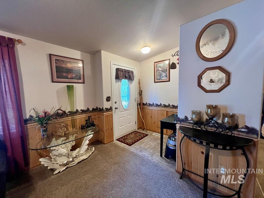 Entryway with vaulted ceiling, carpet, and a wainscoted wall