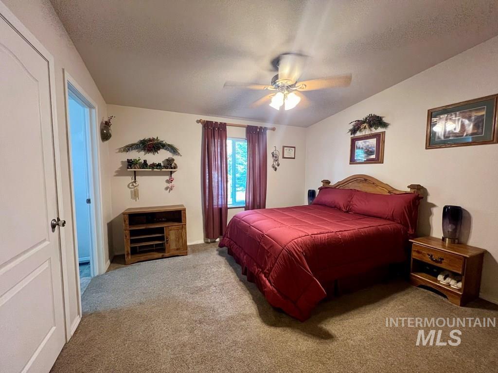 Carpeted bedroom featuring ceiling fan and a textured ceiling