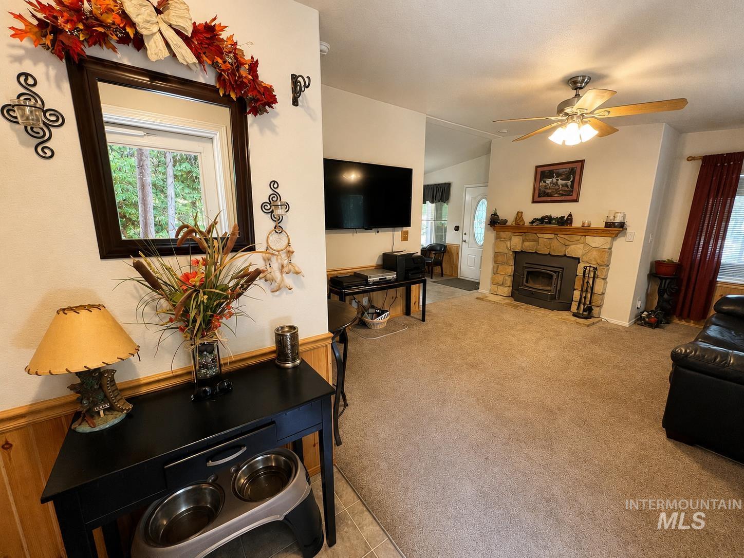 Living room featuring a stone fireplace with a wood-burning insert, recessed lighting, and a ceiling fan