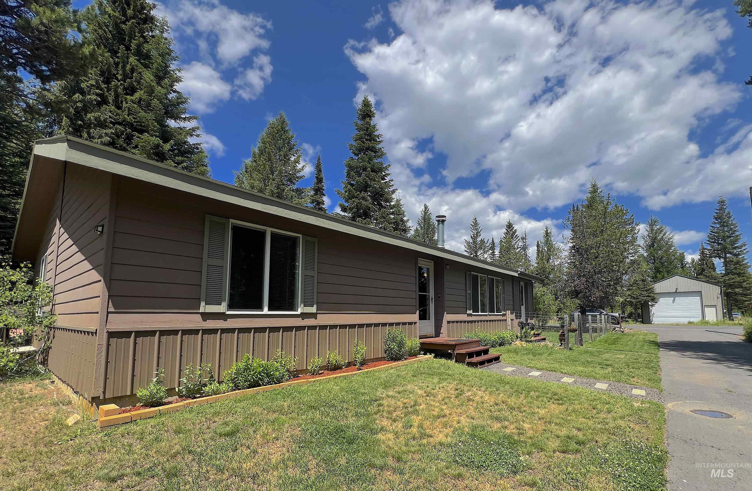 Single story home featuring a front yard, an outbuilding, and a detached garage