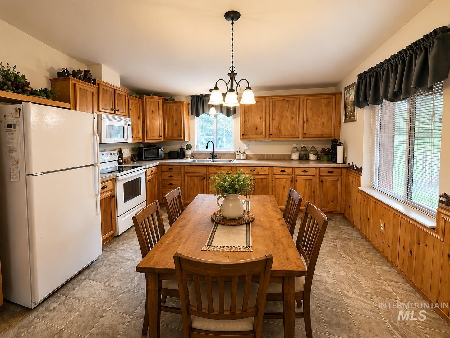 Kitchen featuring wood cabinetry, laminate countertops, and a full suite of white appliances