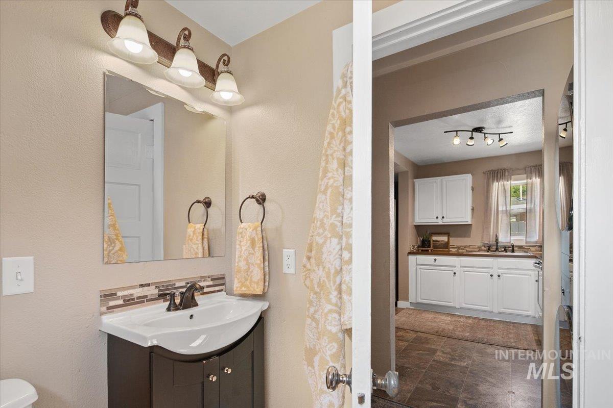 Full bath with two vanities, backsplash, and a textured wall