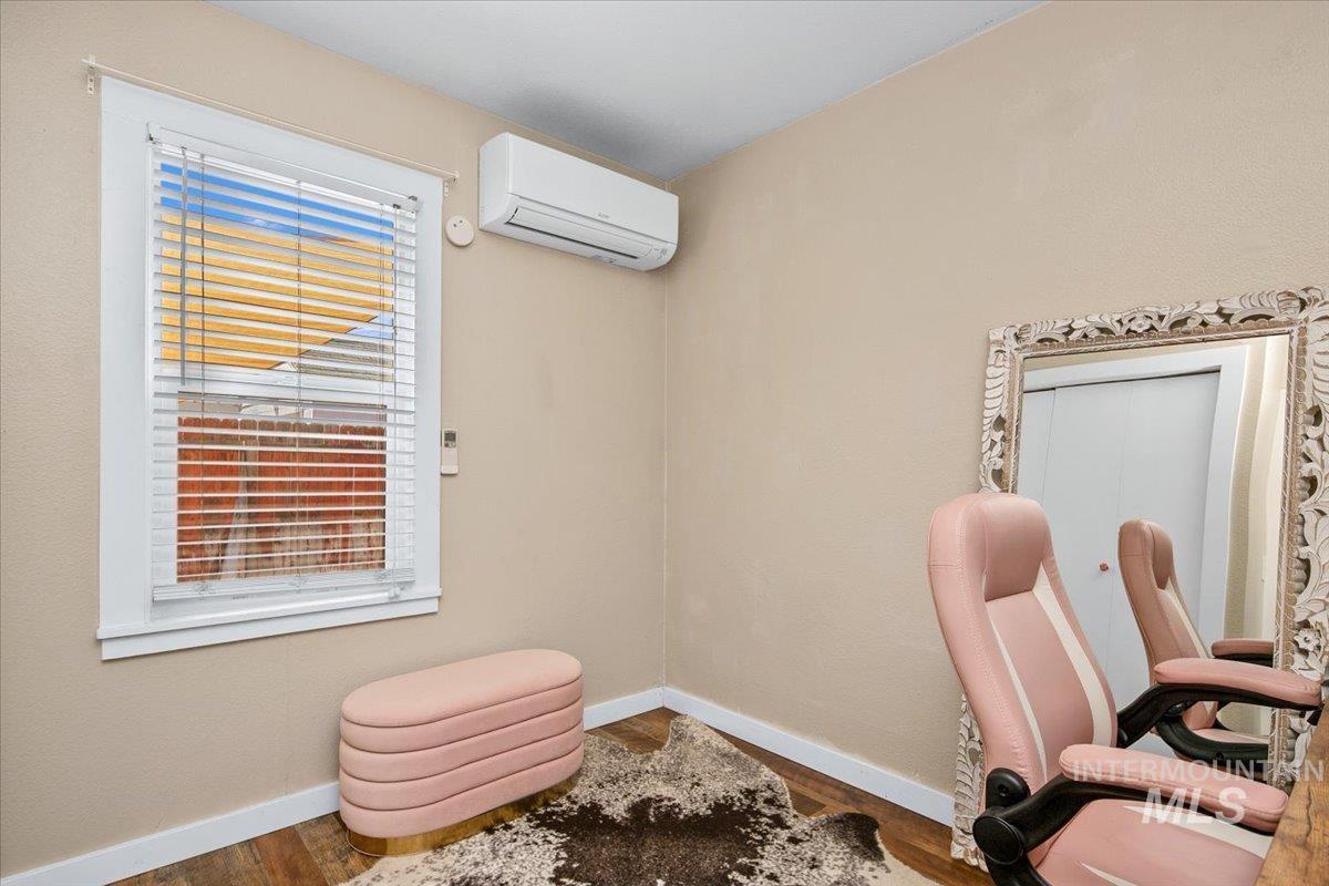 Home office featuring a wall mounted AC and wood finished floors
