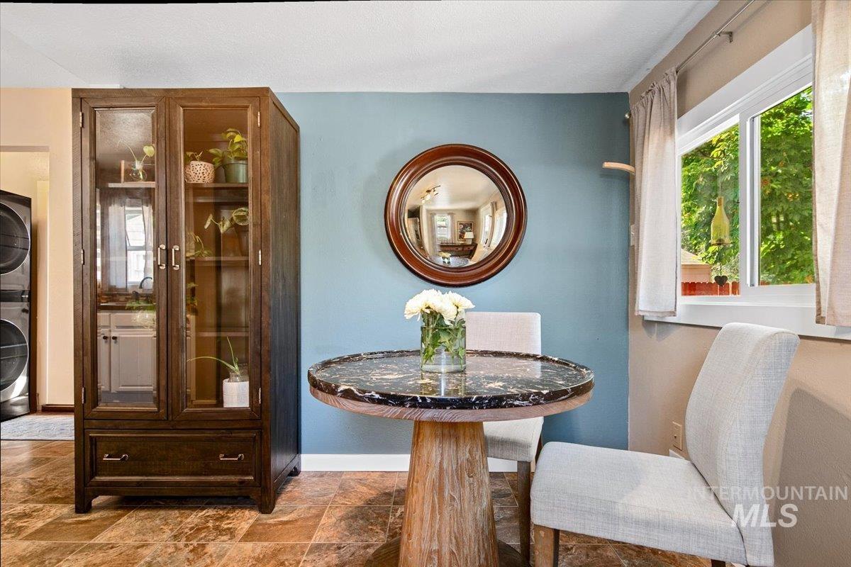 Dining space featuring stone finish flooring and stacked washer and clothes dryer
