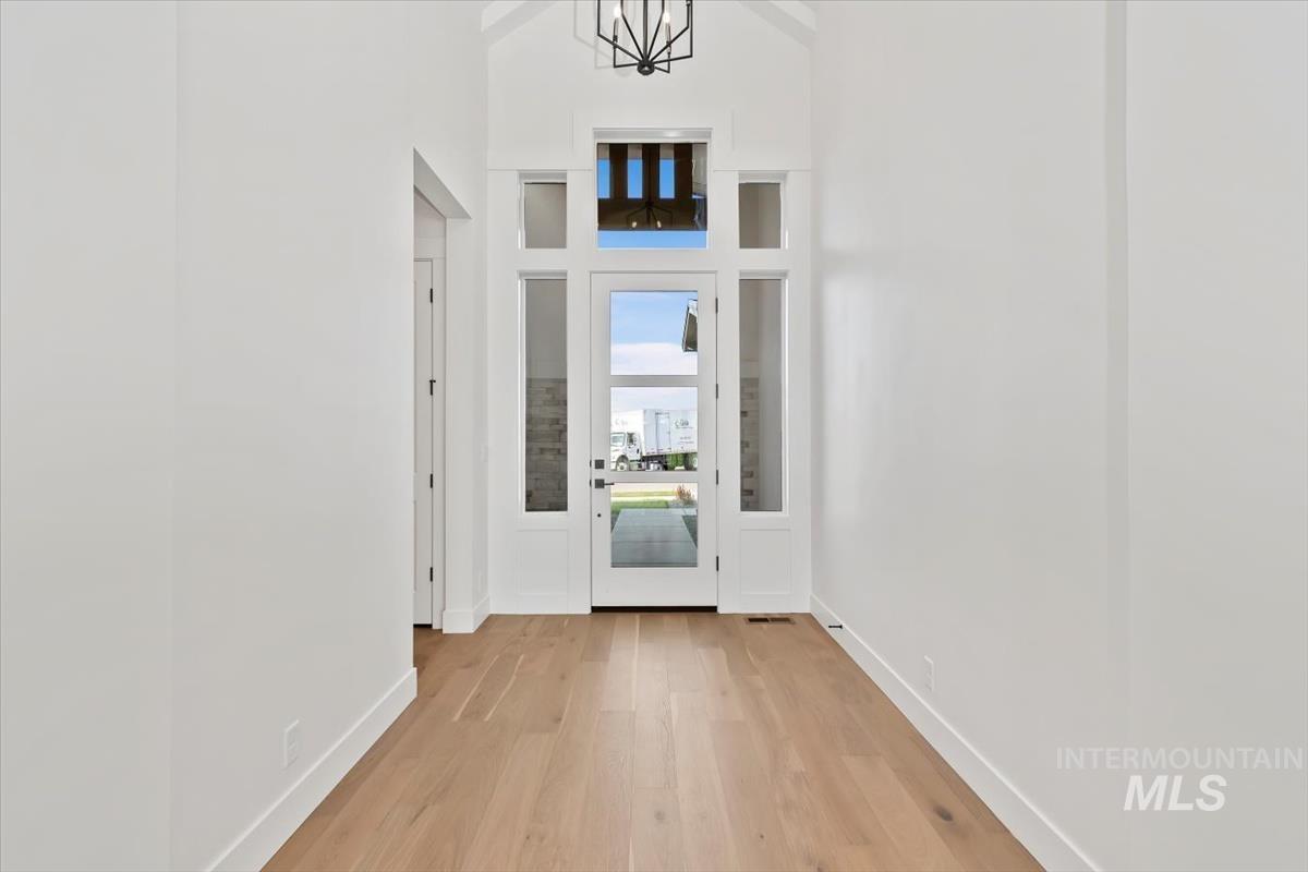 Doorway to outside featuring wood finished floors and a towering ceiling