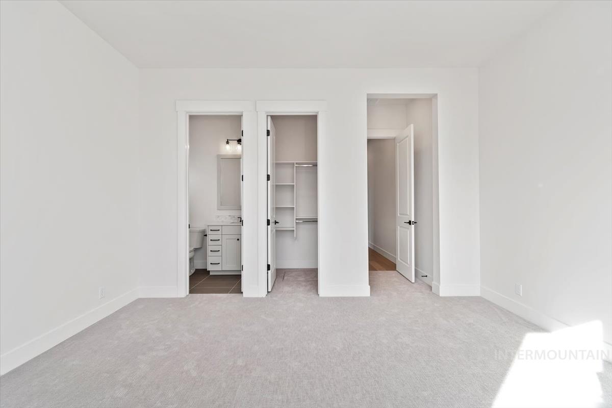 Unfurnished bedroom featuring a walk in closet, light colored carpet, and connected bathroom