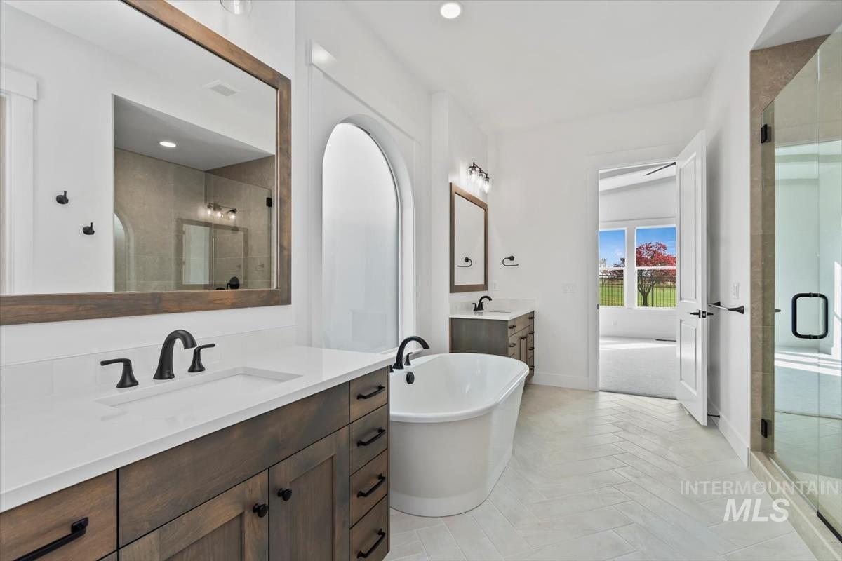 Full bath featuring a soaking tub, two vanities, light tile patterned floors, a shower stall, and recessed lighting