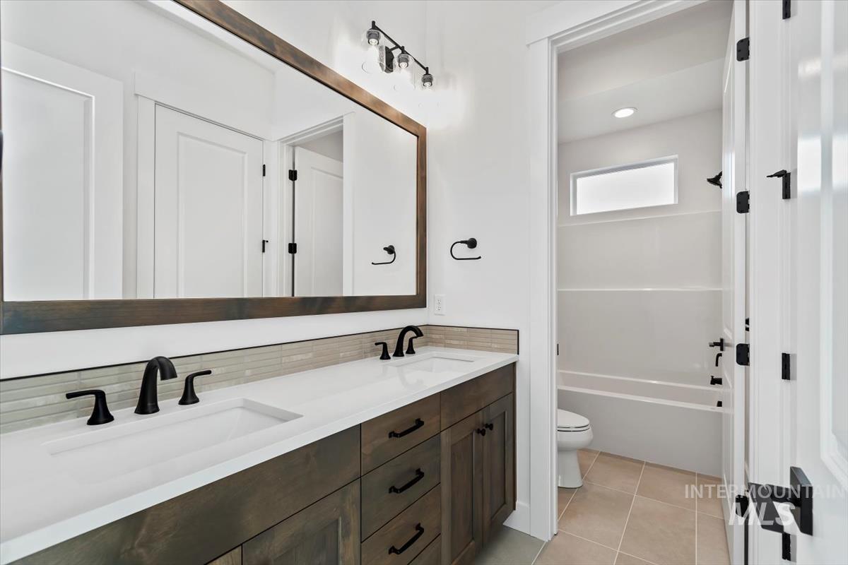 Bathroom featuring double vanity, light tile patterned floors, and a bathtub
