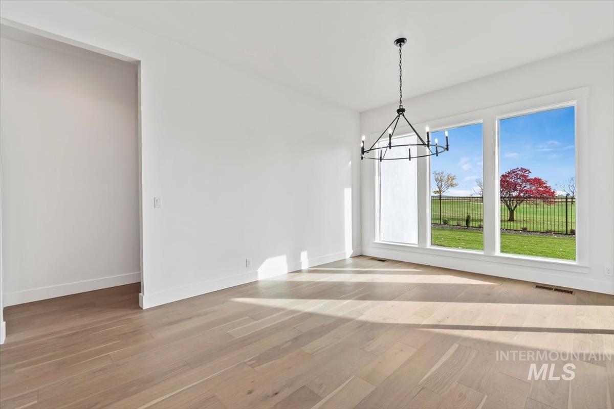 Unfurnished dining area with a chandelier and light wood finished floors