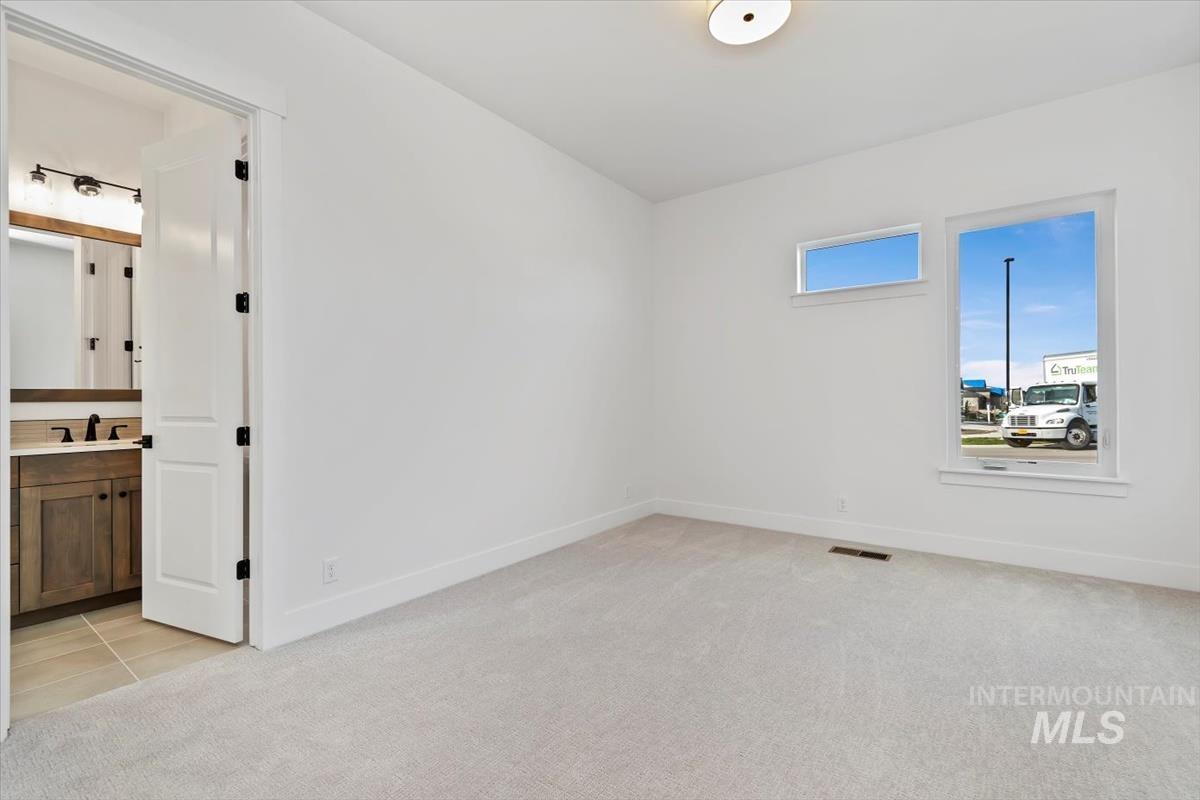 Unfurnished room featuring light carpet and light tile patterned floors