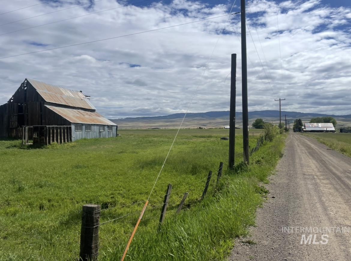 View of dirt / gravel road with a barn, a rural view, and a mountain view