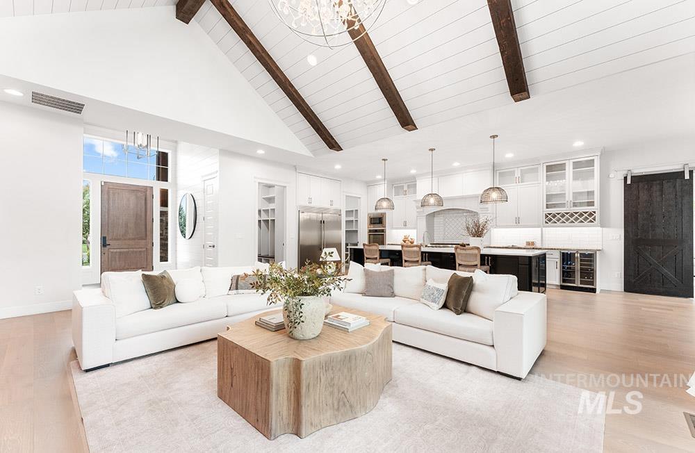 Living area with a chandelier, high vaulted ceiling, a barn door, light wood-style flooring, and recessed lighting