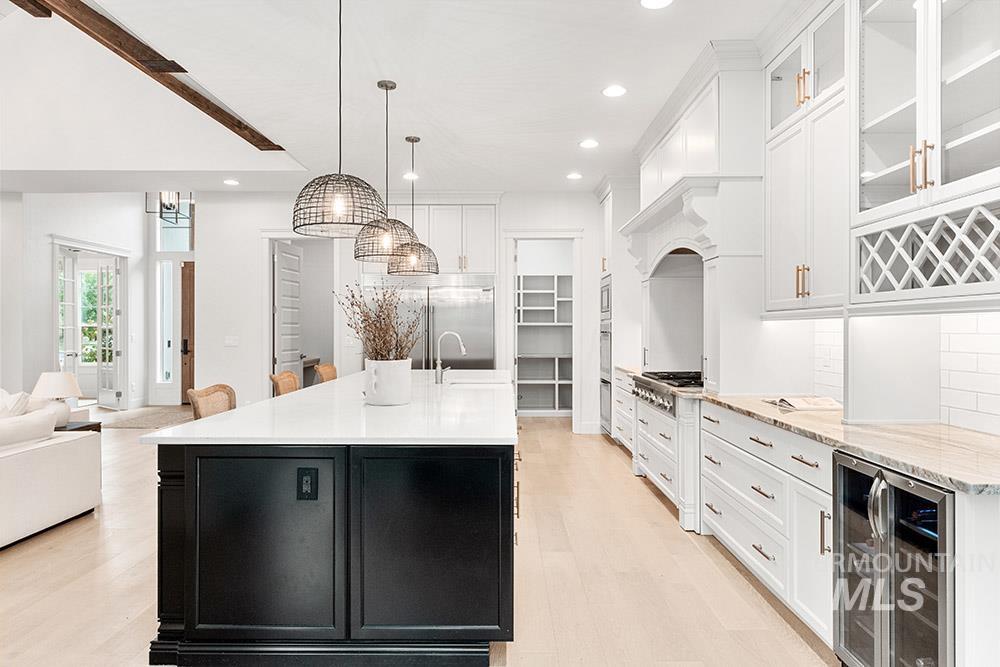 Kitchen with dark cabinets, tasteful backsplash, beverage cooler, white cabinetry, and open floor plan