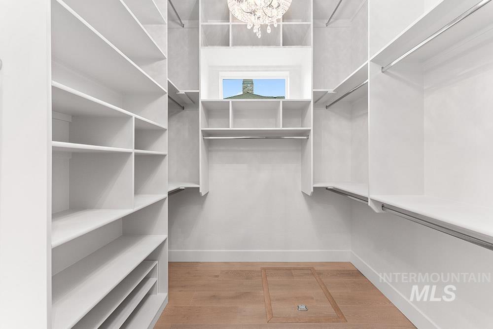 Spacious closet with light wood-style floors and a chandelier