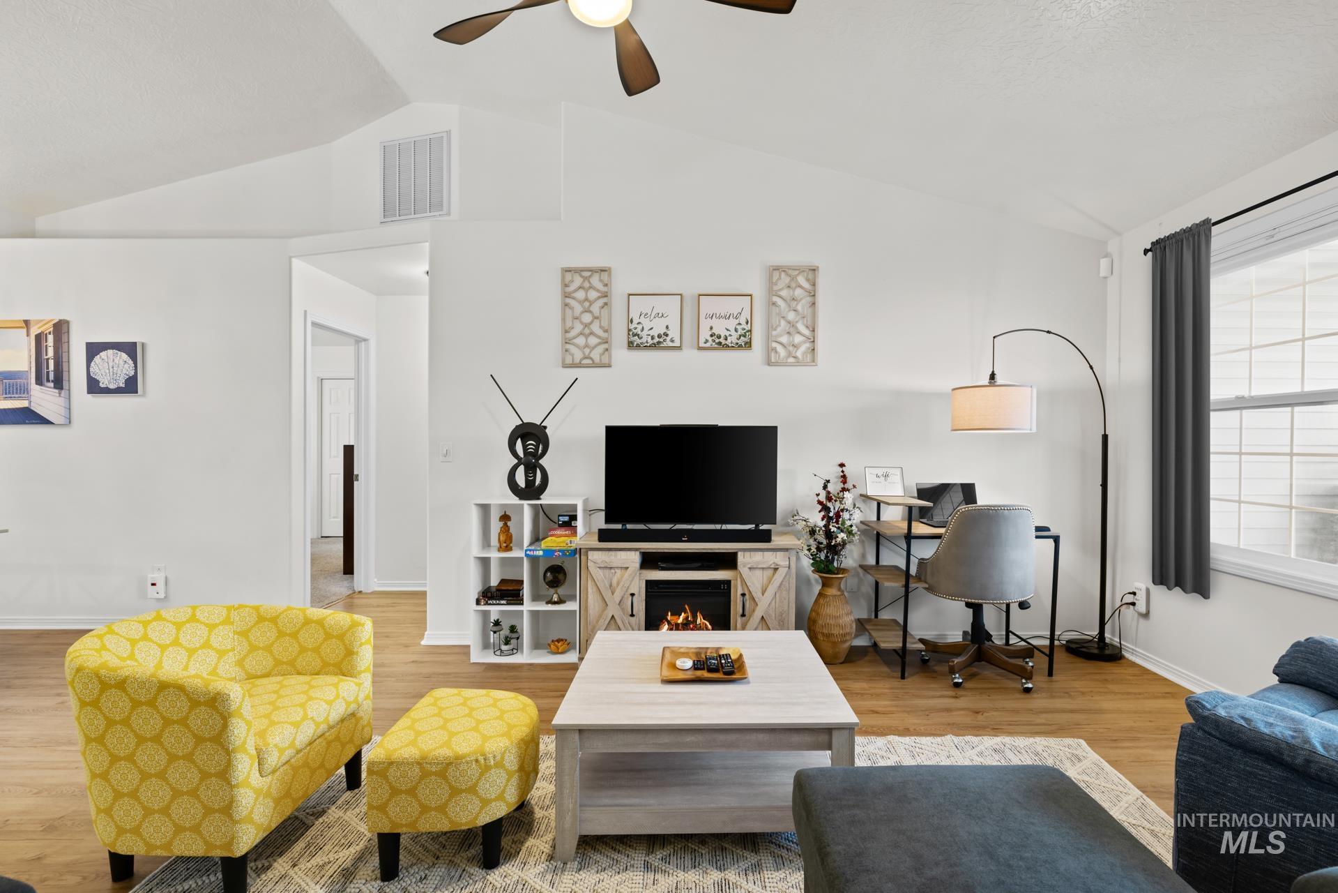 Living room featuring vaulted ceiling, light wood finished floors, and a ceiling fan