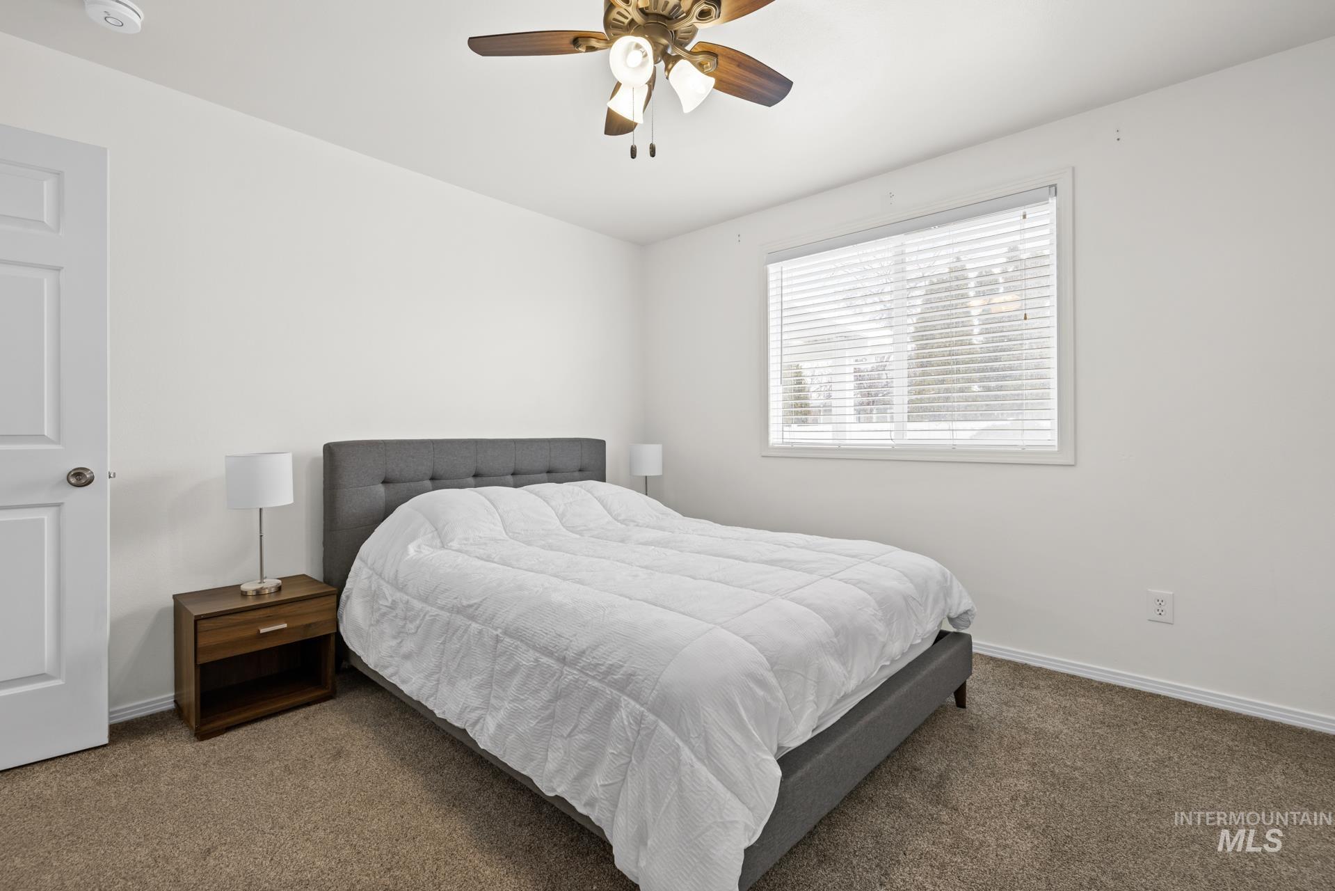 Carpeted bedroom with a ceiling fan and baseboards