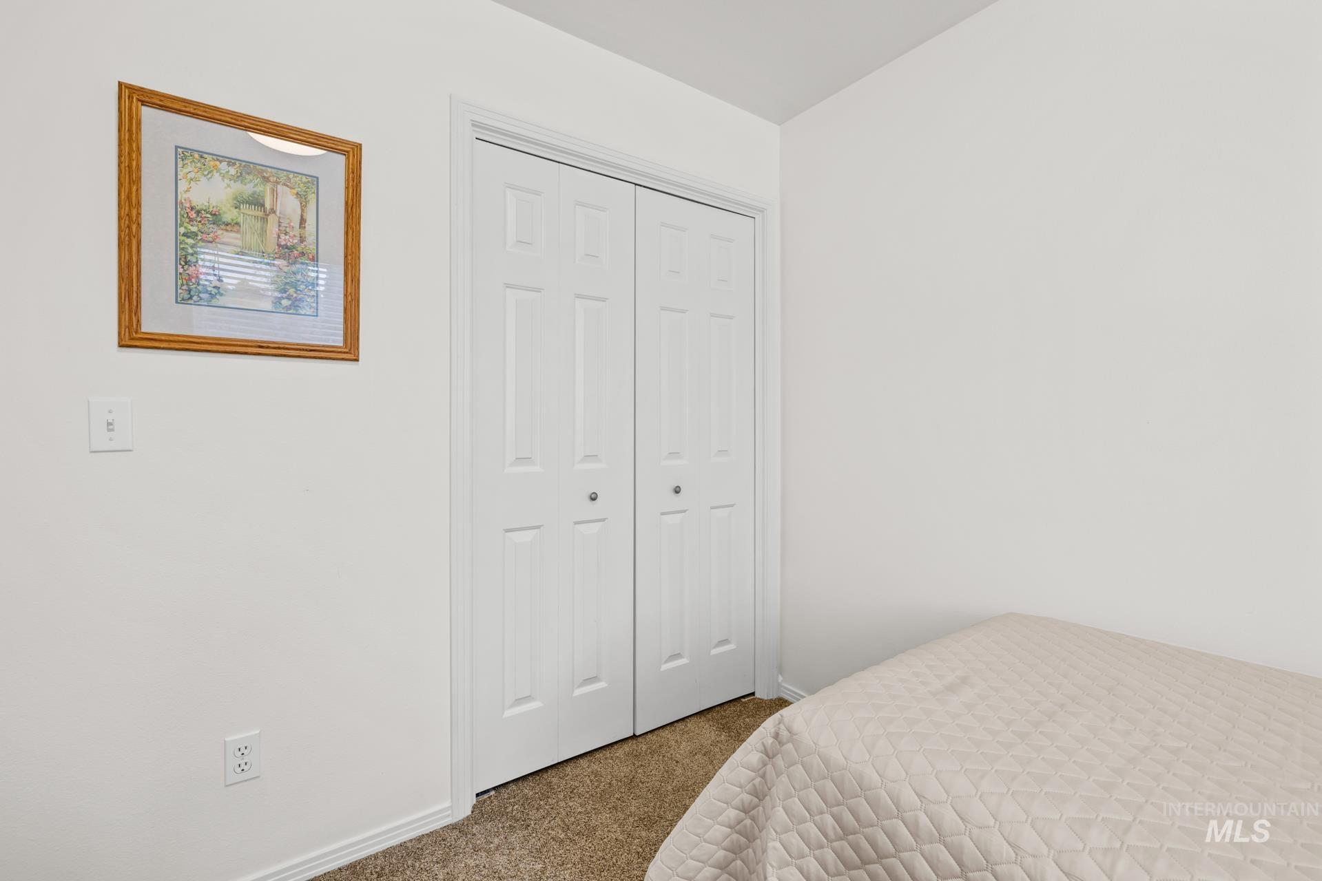 Bedroom with dark colored carpet and a closet