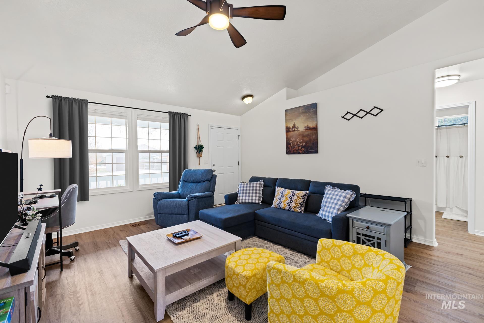 Living area featuring vaulted ceiling, ceiling fan, wood finished floors, and a desk