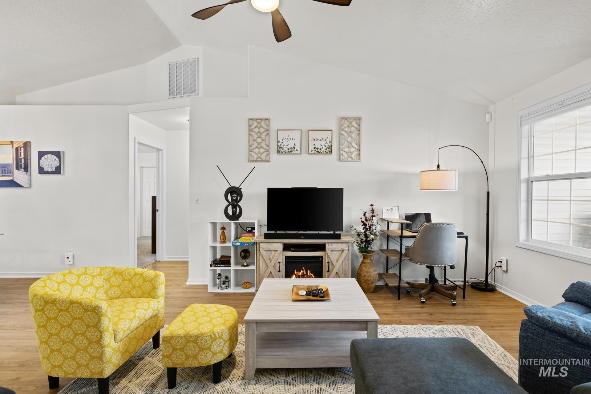 Living area with vaulted ceiling, light wood-style floors, and ceiling fan