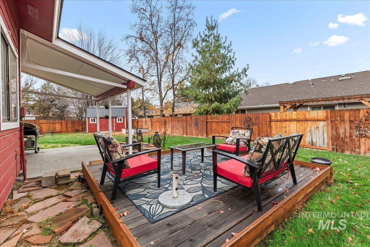 Deck with a fenced backyard, an outdoor hangout area, a patio, an outdoor structure, and a grill